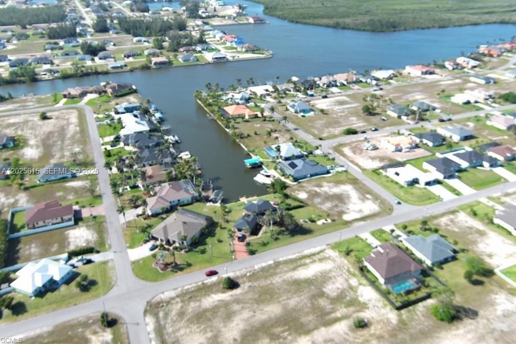 This aerial view shows a residential neighborhood with houses situated along a canal — CAPE CORAL, FL