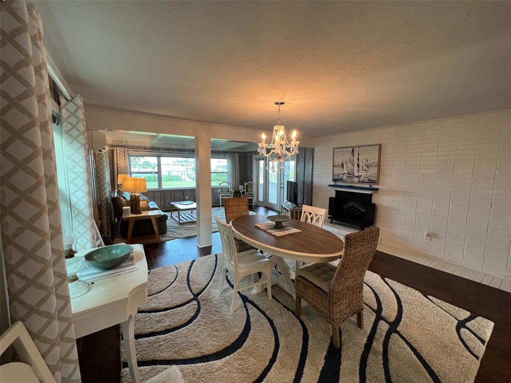 A dining area with a chandelier and oval table sits before a living room space — 1626 NEW POINT COMFORT ROAD, ENGLEWOOD, FL