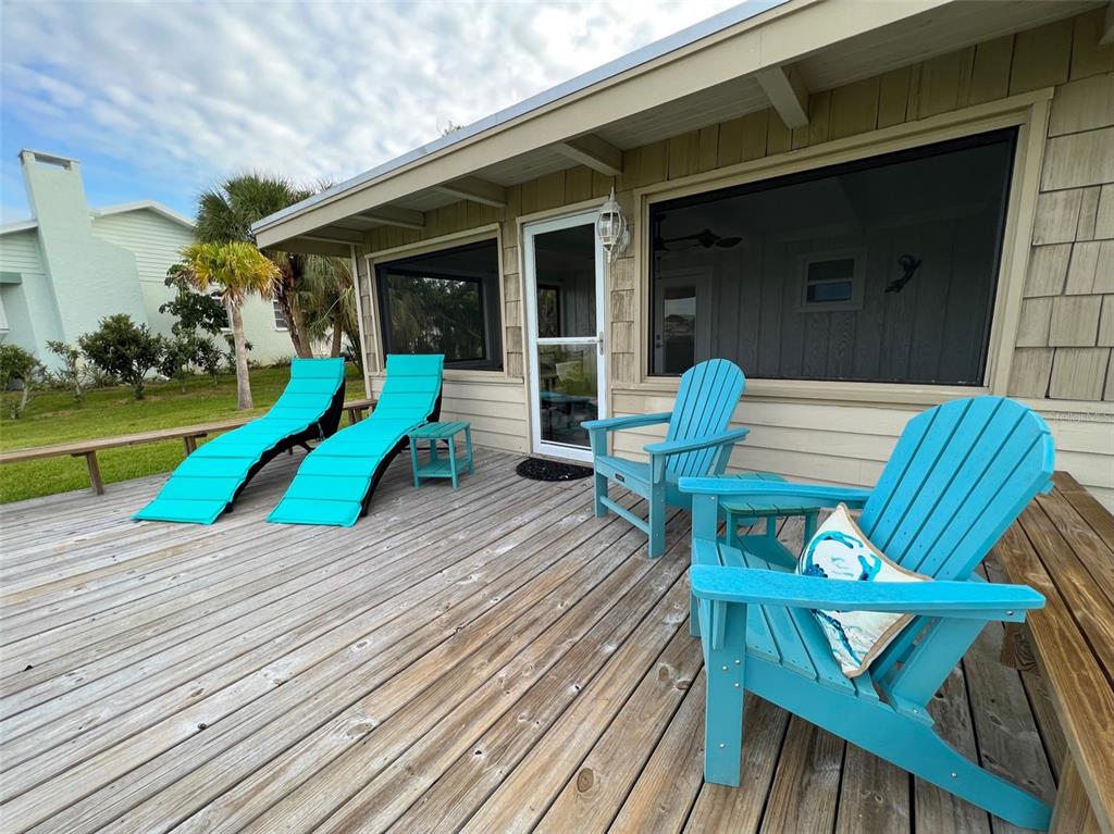 A wooden deck features four bright blue chairs and a small table outside a house — 1626 NEW POINT COMFORT ROAD, ENGLEWOOD, FL
