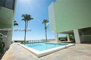 A swimming pool sits between two light green buildings with palm trees under a blue sky — 87455 Old Hwy # 247, Islamorada FL 33036, ISLAMORADA, FL
