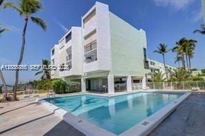 A multi-story white apartment building stands behind a rectangular swimming pool on a sunny day — 87455 Old Hwy # 247, Islamorada FL 33036, ISLAMORADA, FL