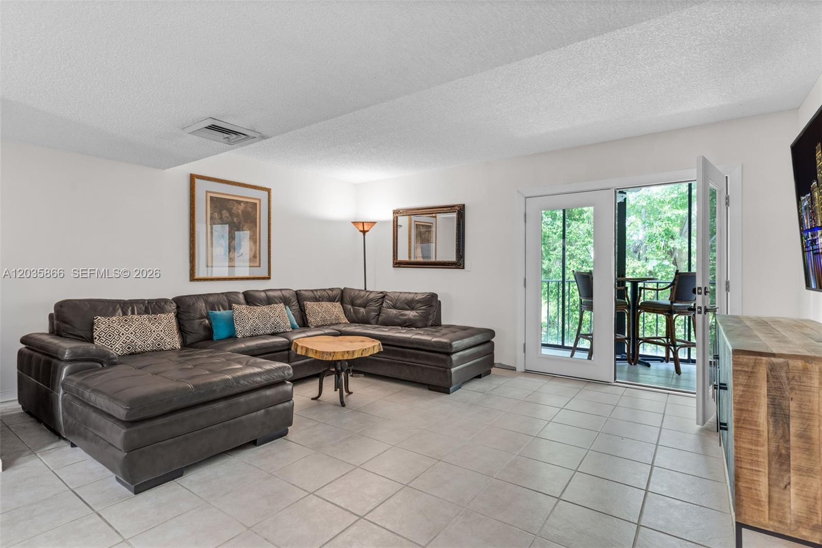 A living room features a large dark leather sectional, tile flooring, and a glass door — 87455 Old Hwy # 247, Islamorada FL 33036, ISLAMORADA, FL