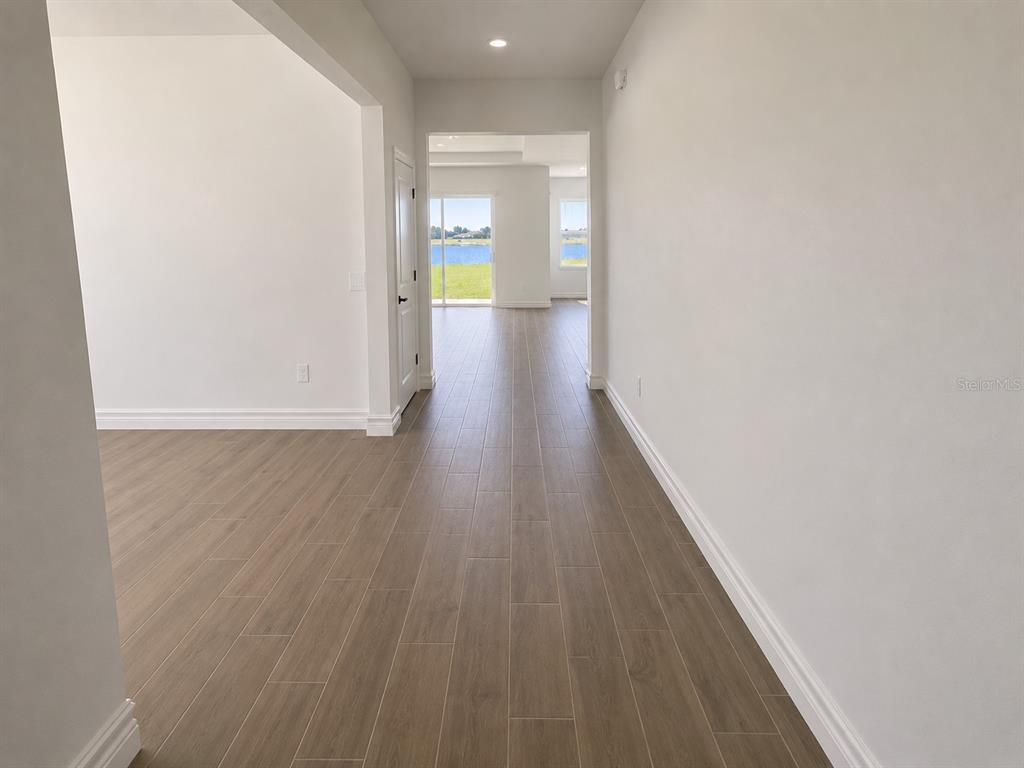A hallway with wood-look tile flooring leads toward a room with a view of water — 12558 COLONNADE VISTA DRIVE, RIVERVIEW, FL