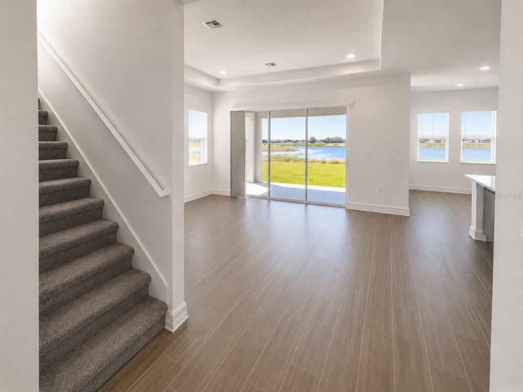 An interior view shows a carpeted staircase next to a living area with water views — 12558 COLONNADE VISTA DRIVE, RIVERVIEW, FL
