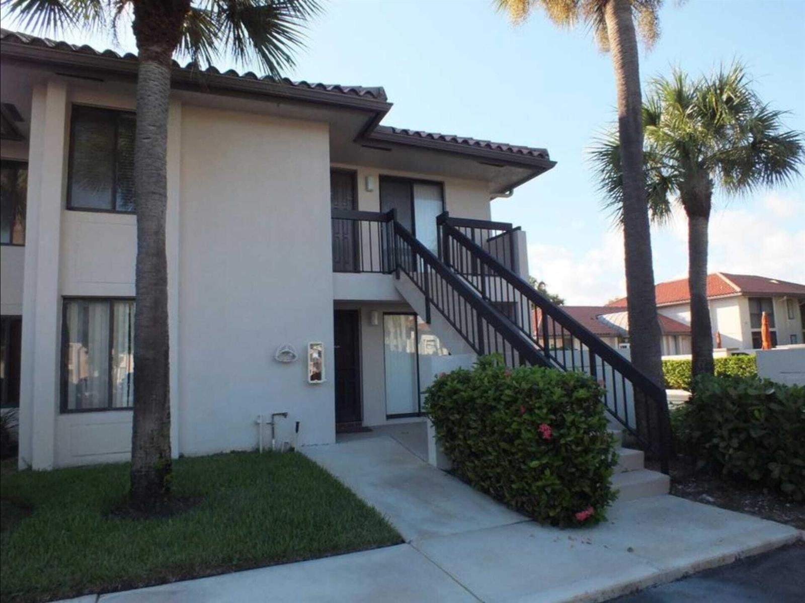 A two-story apartment building exterior with a concrete walkway, stairs, and palm trees — 300 E Club Circle # 201, Boca Raton FL 33487, BOCA RATON, FL