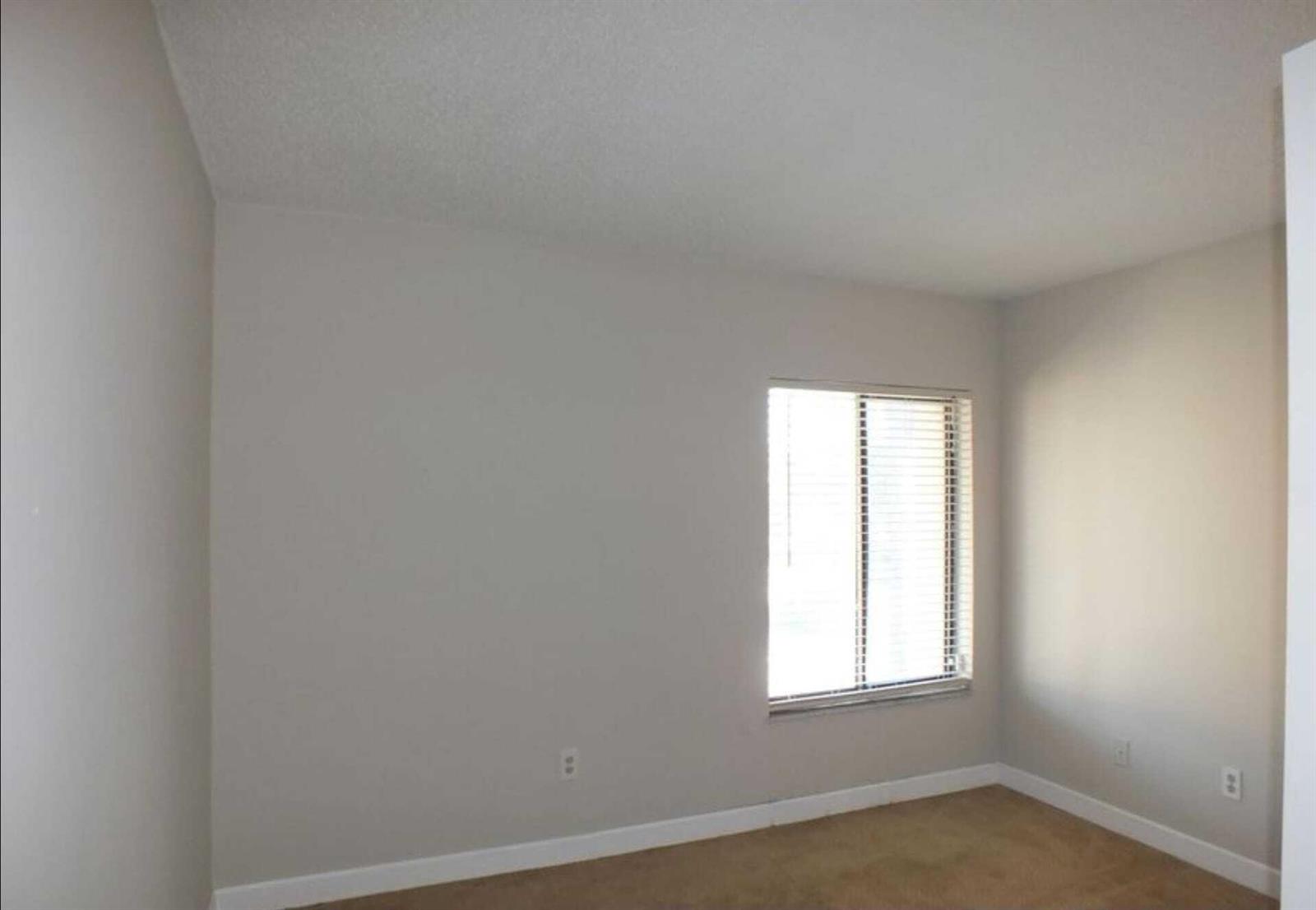 An empty bedroom with beige walls, tan carpet, and a window with white blinds — 300 E Club Circle # 201, Boca Raton FL 33487, BOCA RATON, FL