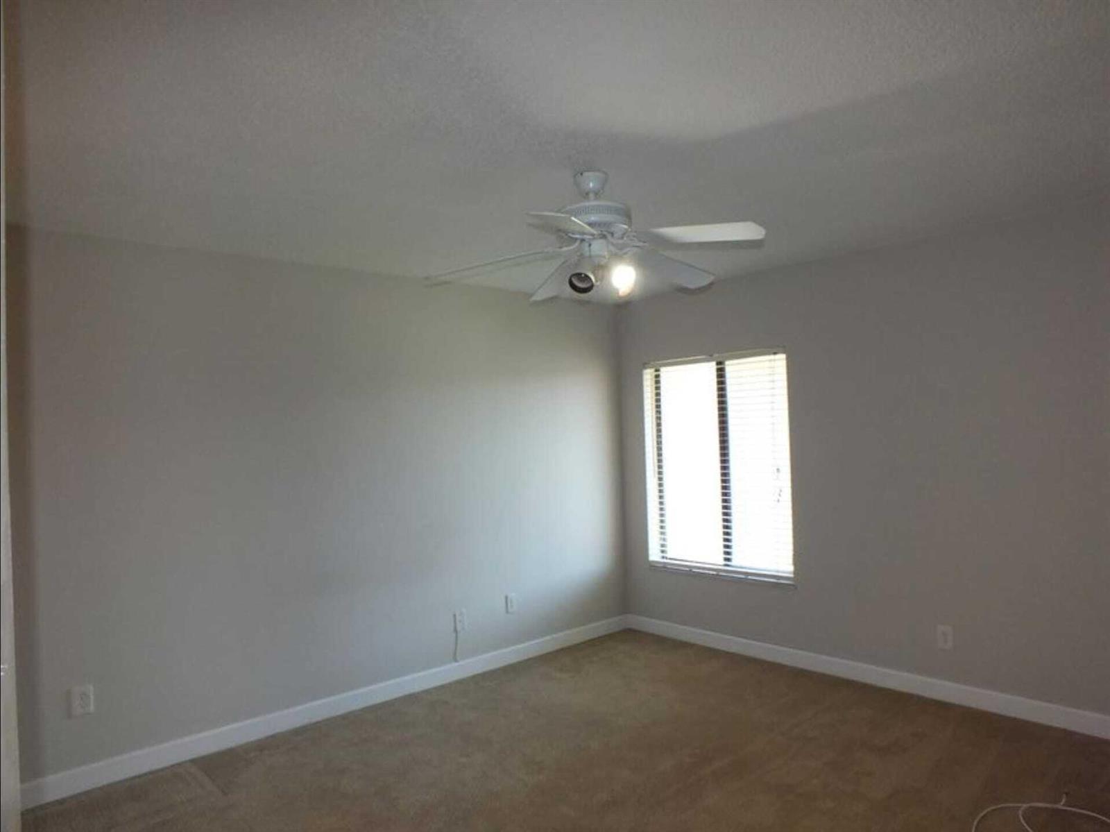 An empty bedroom features beige carpet, light gray walls, and a white ceiling fan — 300 E Club Circle # 201, Boca Raton FL 33487, BOCA RATON, FL