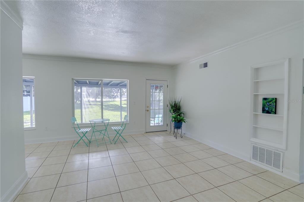 A bright room with white walls, tile flooring, a glass door, and built-in wall shelving — 121 S TRIPLET LAKE DRIVE, CASSELBERRY, FL