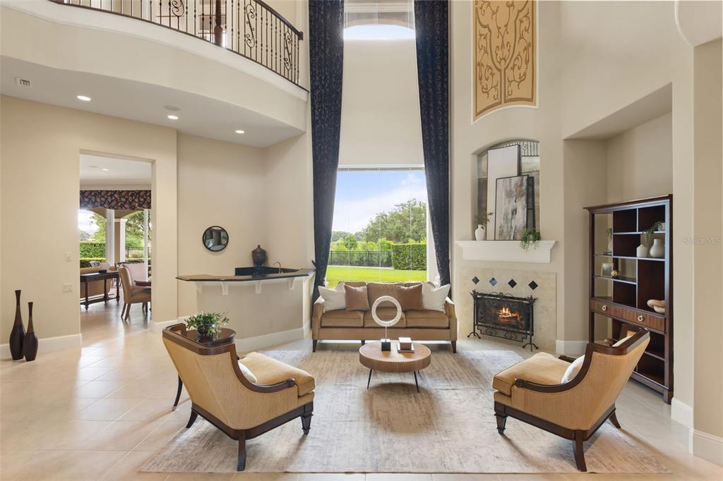 A two-story living room features a fireplace, a wet bar, and large windows with curtains — 26010 ESTATES RIDGE DRIVE, SORRENTO, FL