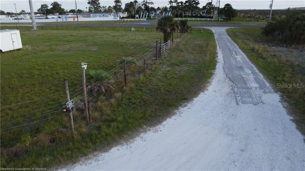 An aerial view shows a dirt driveway leading to a fenced, grassy vacant lot — 300 SR-70 E, LAKE PLACID, FL