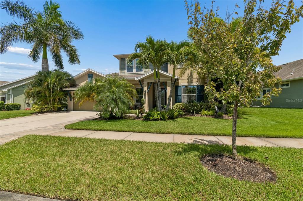 A two-story suburban house with a tan exterior, palm trees, and a concrete driveway — 6323 HAVENSPORT DRIVE, APOLLO BEACH, FL
