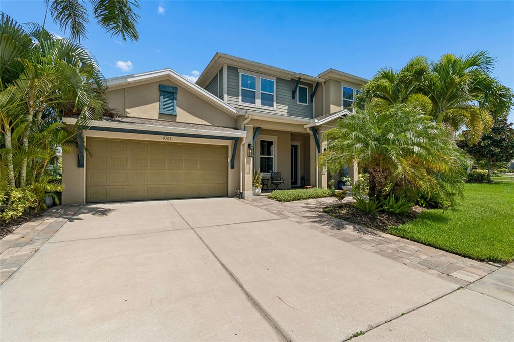 A two-story suburban house with a tan stucco exterior, a two-car garage, and palm trees — 6323 HAVENSPORT DRIVE, APOLLO BEACH, FL