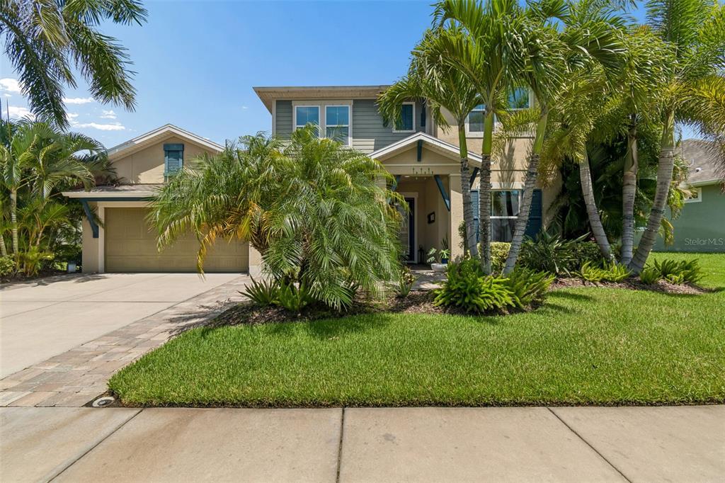 A two-story house with a tan garage, palm trees, and a green lawn — 6323 HAVENSPORT DRIVE, APOLLO BEACH, FL