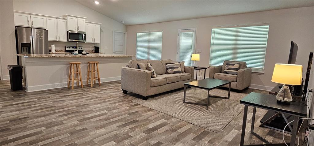 An open-concept living room features a kitchen with white cabinets and a gray sofa — 137 ULLIAN TRAIL, PALM COAST, FL