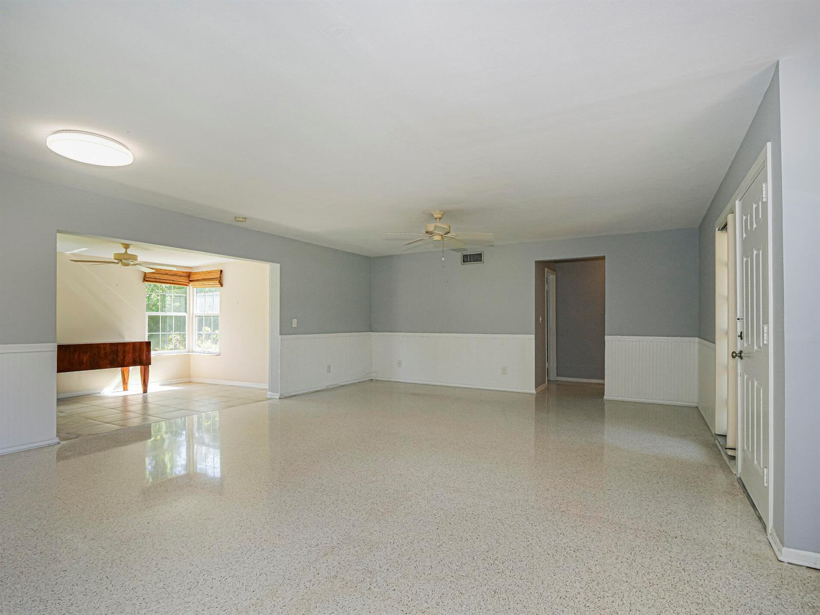 A spacious living room features light gray walls, white wainscoting, and polished terrazzo flooring — 2616 15th Street, Vero Beach FL 32960, VERO BEACH, FL