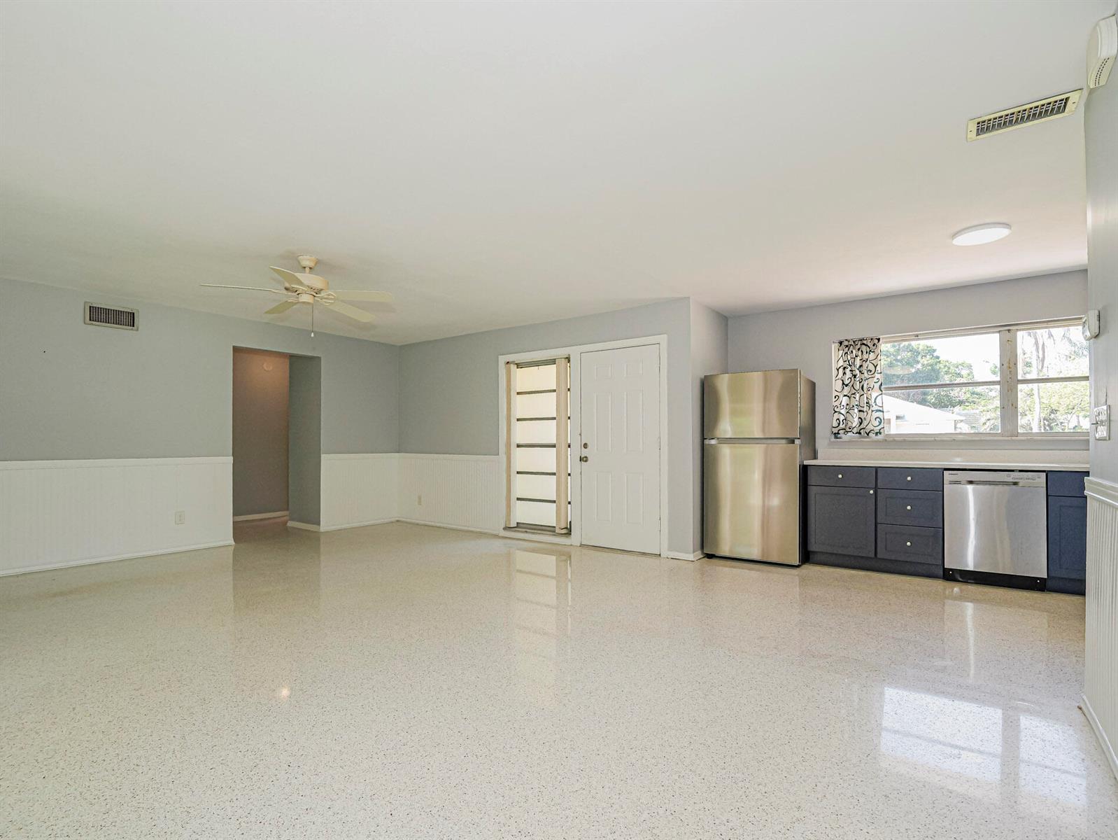 An open-concept kitchen and living area features light gray walls, white wainscoting, and terrazzo flooring — 2616 15th Street, Vero Beach FL 32960, VERO BEACH, FL