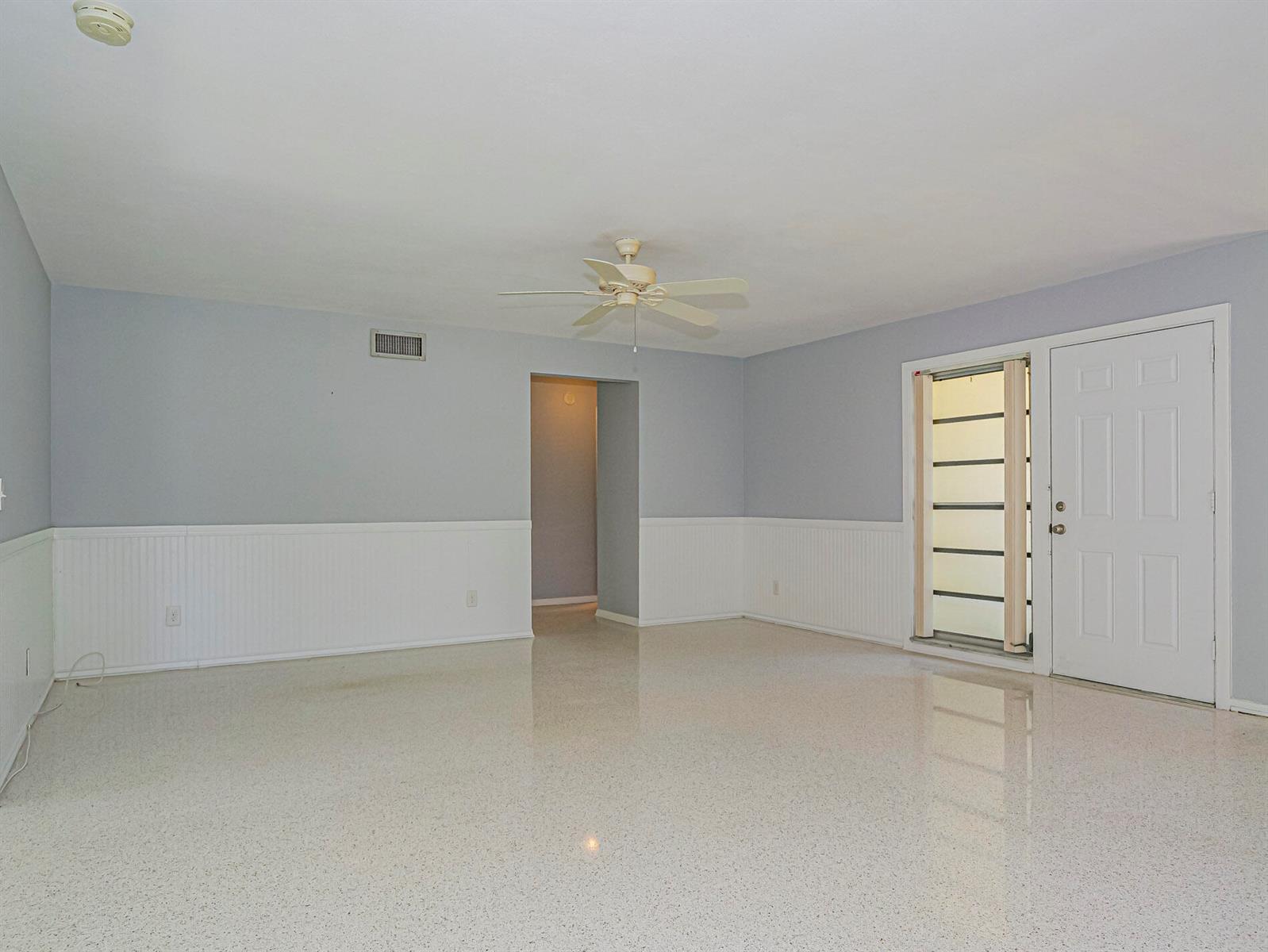 An empty room features light blue walls, white wainscoting, a ceiling fan, and terrazzo flooring — 2616 15th Street, Vero Beach FL 32960, VERO BEACH, FL
