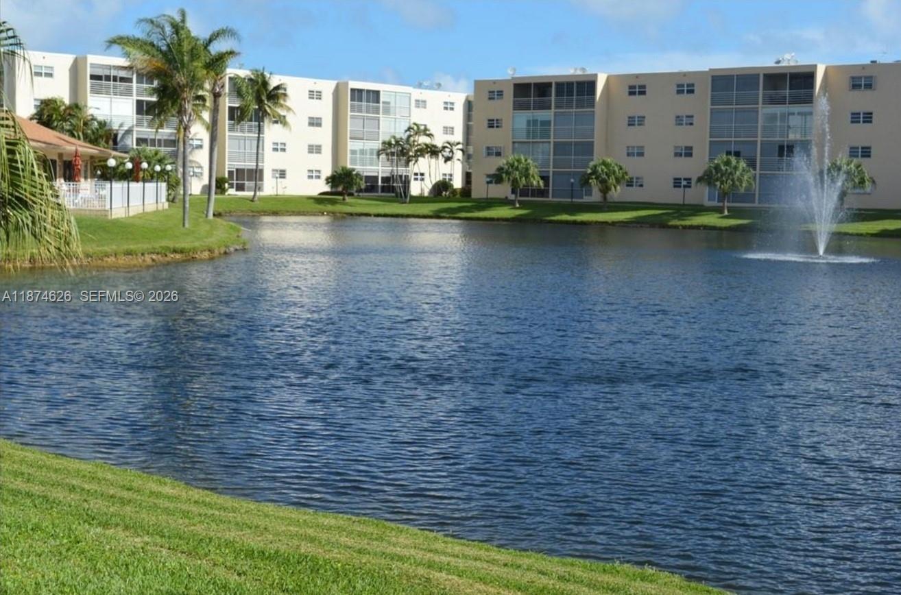 A multi-story apartment building overlooks a pond with a fountain and landscaped grounds — 425 SE 11th Ter # 403, Dania Beach FL 33004, DANIA BEACH, FL