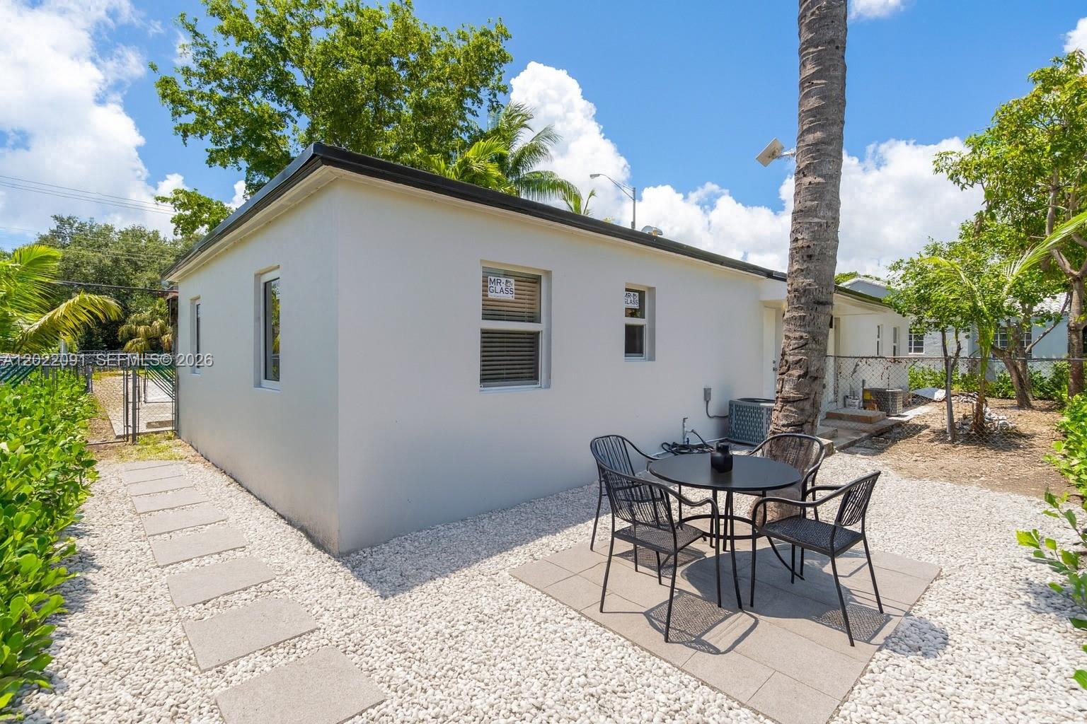 A white exterior wall with windows and a small patio area with outdoor furniture — 351 NE 82nd St # 1, Miami FL 33138, MIAMI, FL