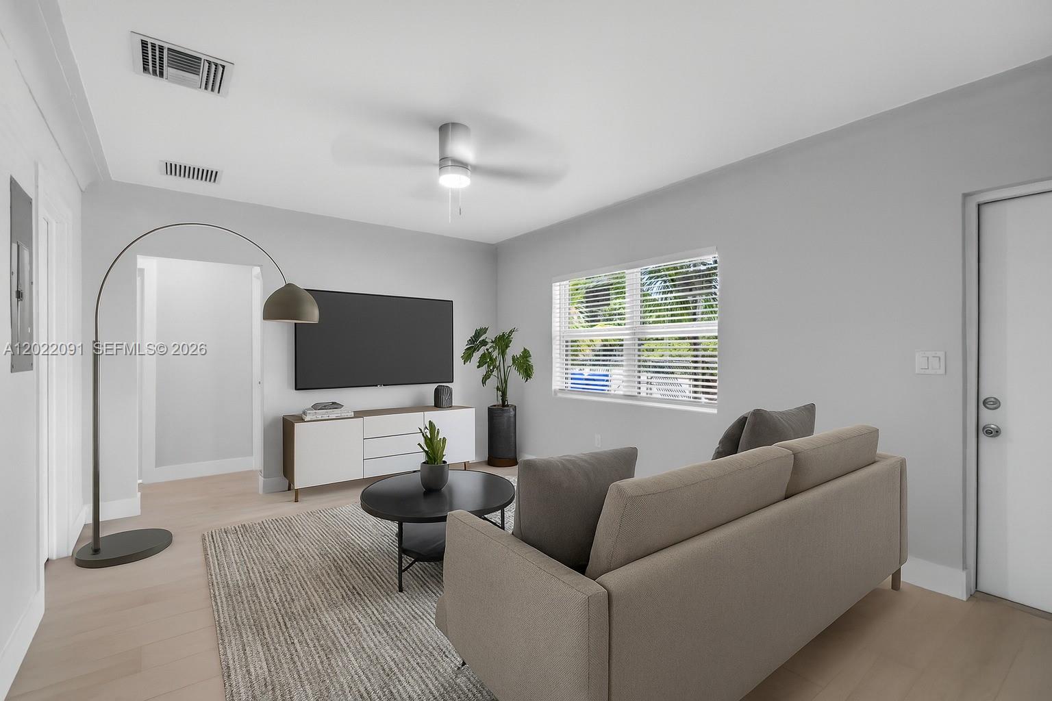 A living room features a grey sofa, a television on a console, and a floor lamp — 351 NE 82nd St # 1, Miami FL 33138, MIAMI, FL