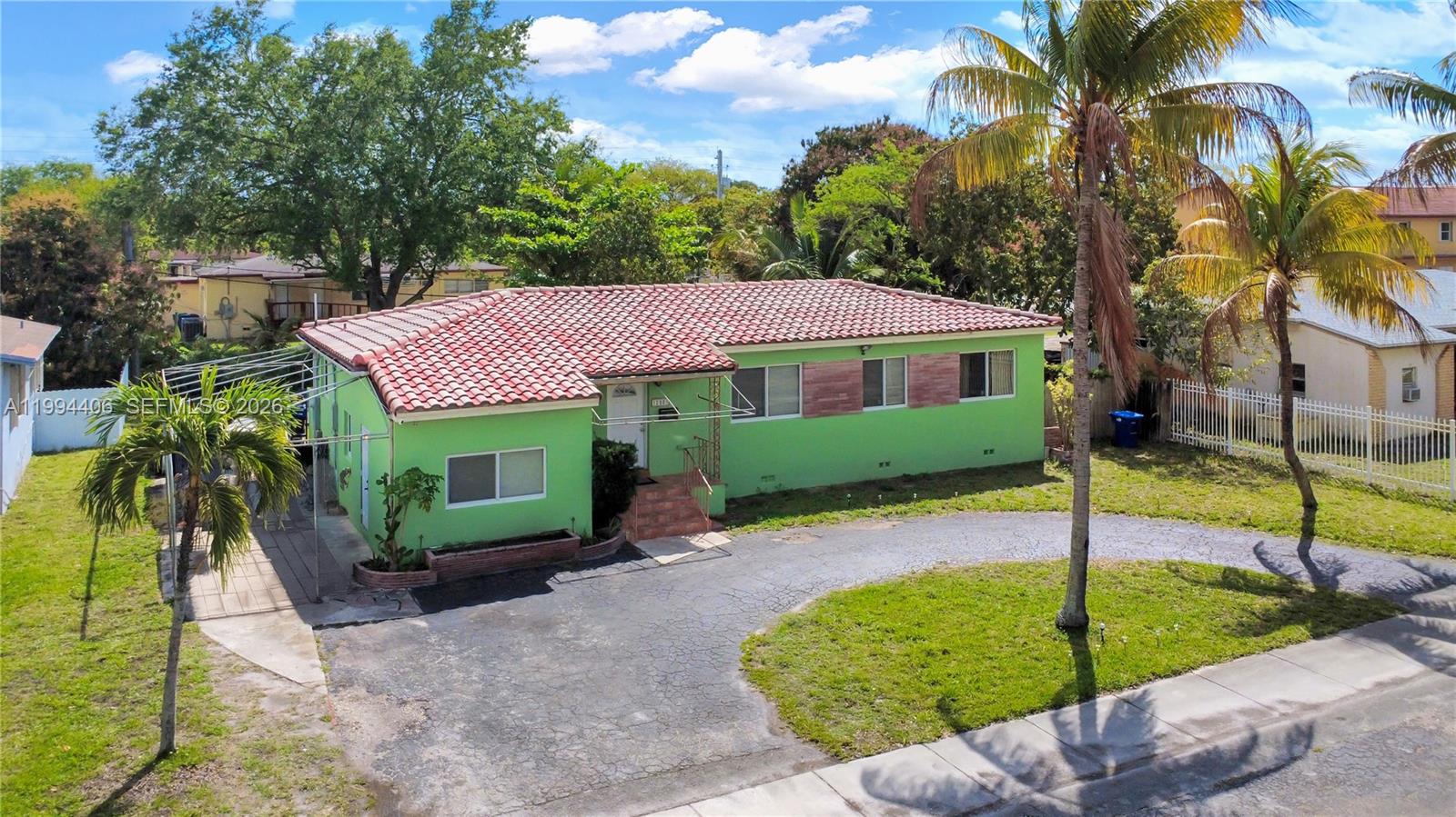 A lime green single-story house features a red tile roof and a curved asphalt driveway — 12901 NW Miami Ct, Miami FL 33168, MIAMI, FL
