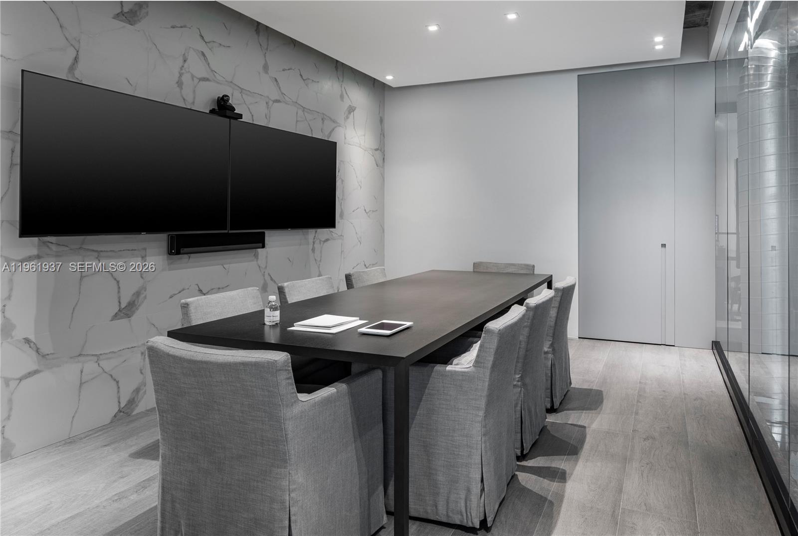 A modern conference room features a long table, gray upholstered chairs, and a marble-patterned wall — 2347 Biscayne Blvd # 7, Miami FL 33137, MIAMI, FL