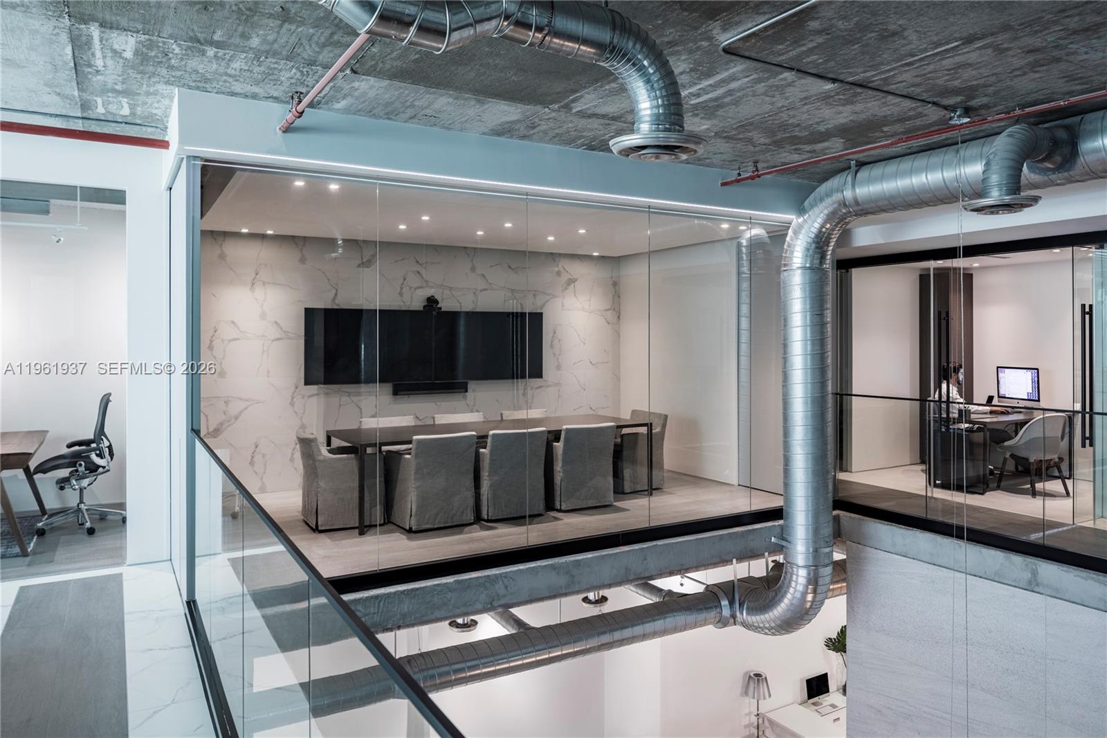 A modern office interior features glass-walled conference rooms with exposed ductwork and concrete ceilings — 2347 Biscayne Blvd # 7, Miami FL 33137, MIAMI, FL