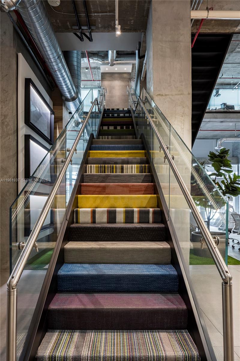 An indoor staircase features multi-colored carpeted treads, glass railings, and an industrial-style exposed ceiling — 2347 Biscayne Blvd # 7, Miami FL 33137, MIAMI, FL