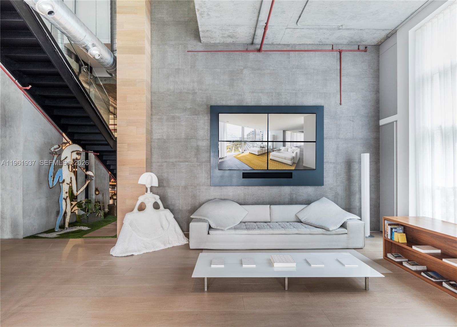 A modern living room features a concrete wall, a multi-screen display, and a white sofa — 2347 Biscayne Blvd # 7, Miami FL 33137, MIAMI, FL