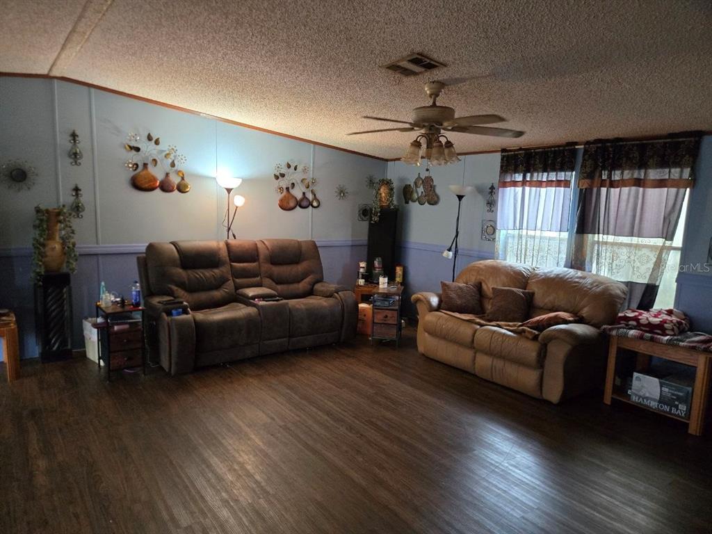 A living room features two brown sofas, wood-look flooring, and light blue walls — 8323 FANTASIA PARK WAY, RIVERVIEW, FL