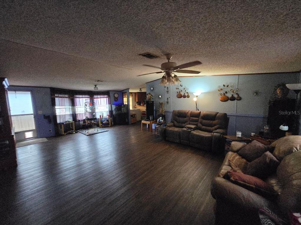 A spacious living room features dark wood-look flooring, blue walls, and a ceiling fan — 8323 FANTASIA PARK WAY, RIVERVIEW, FL