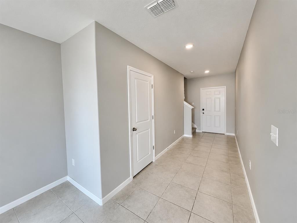 A tiled entryway features a white door, a closet door, and stairs in the background — 16717 DELIA STREET, WIMAUMA, FL