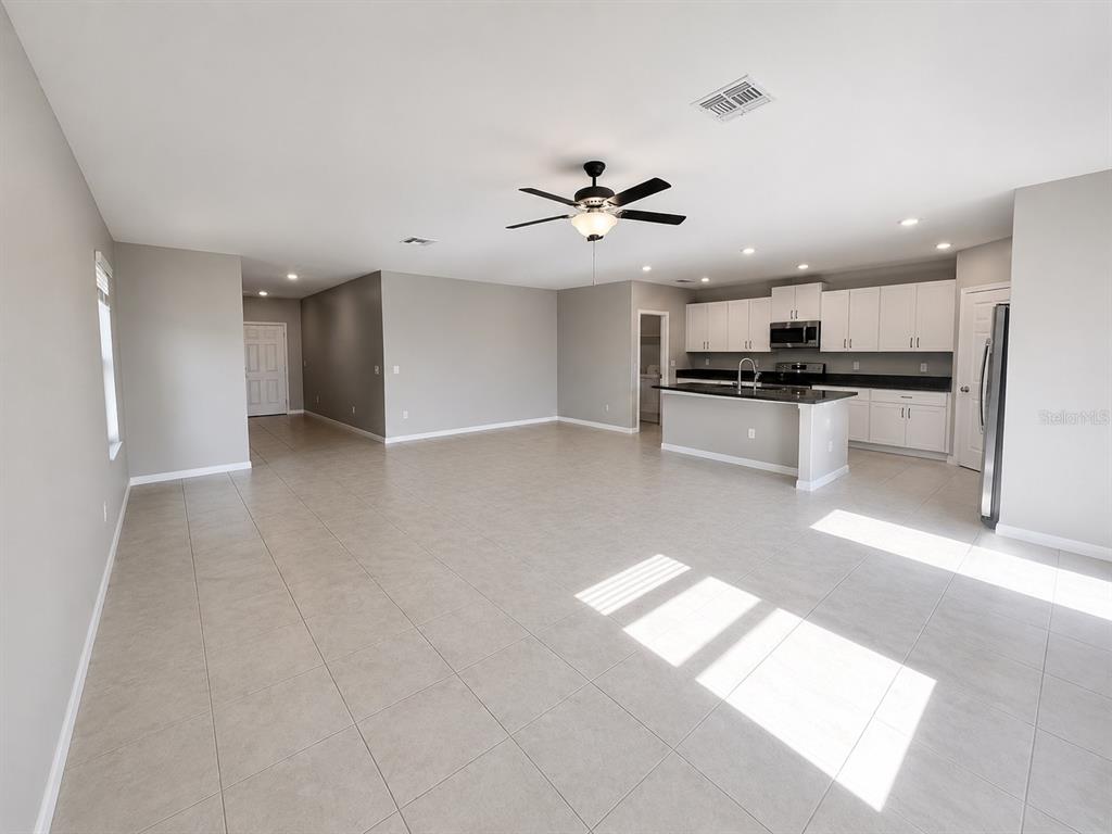 An open-concept kitchen and living area with light tile flooring and white cabinetry — 16717 DELIA STREET, WIMAUMA, FL