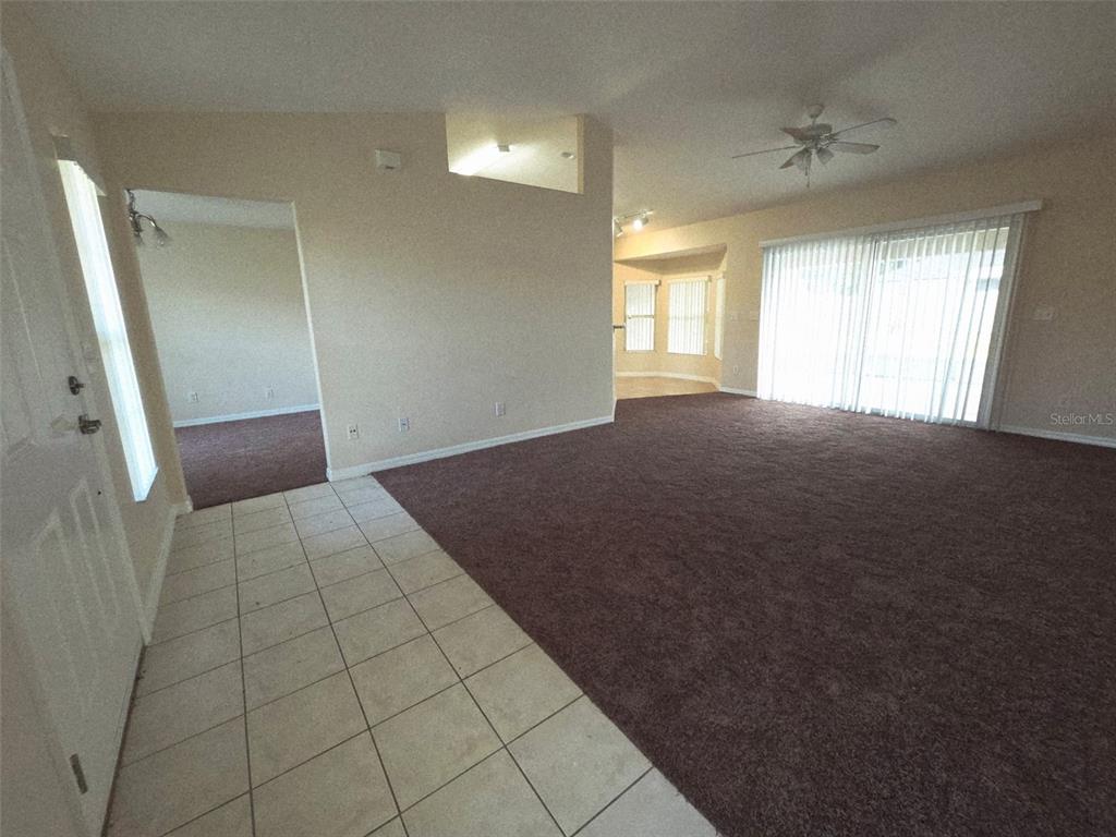 An entryway with tile flooring leads into a carpeted living area with sliding glass doors — 3 PORT LANE, PALM COAST, FL