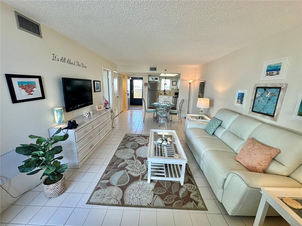 A living room with tile floors, a white sofa, a coffee table, and a dining area — 5915 SEA RANCH DRIVE UNIT 711, HUDSON, FL