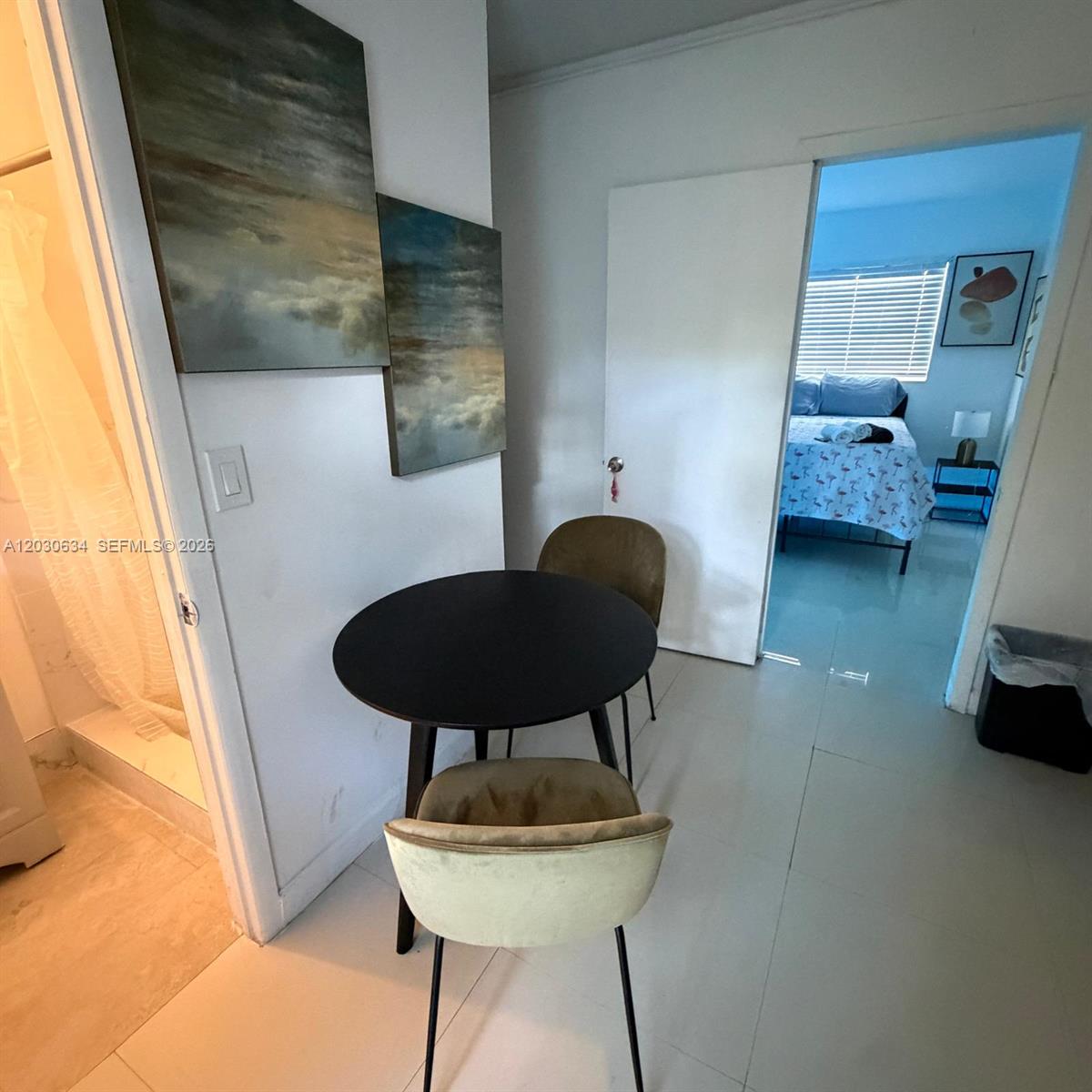 A small dining area with a round table and two chairs sits near a bedroom — 119 SE 9th St # 12, Hallandale Beach FL 33009, HALLANDALE BEACH, FL
