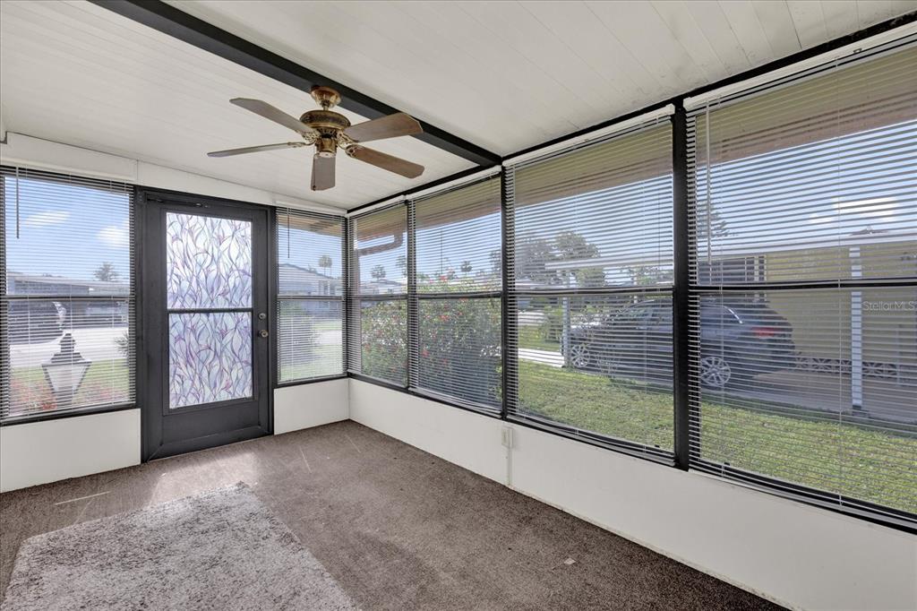 A sunroom with carpeted floors, a ceiling fan, and large windows with horizontal blinds — 415 S TIMBER TRAIL, WILDWOOD, FL