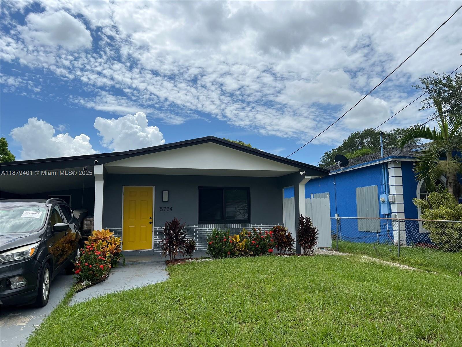 A gray single-story house features a bright yellow front door and a covered porch area — 5724 SW 18th St, West Park FL 33023, WEST PARK, FL