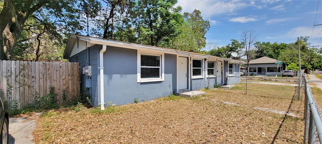 A blue single-story house with a white door and windows sits behind a chain-link fence — 1308 E YUKON STREET UNIT B, TAMPA, FL