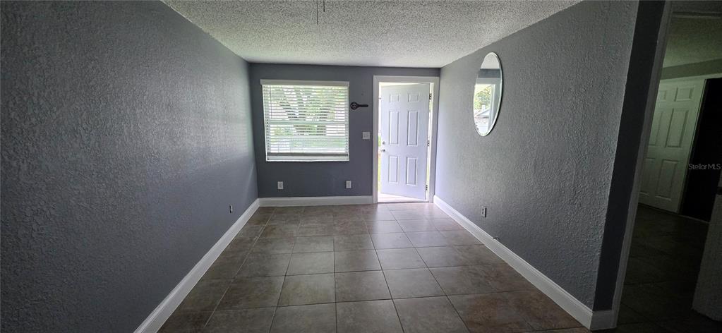 An empty room with gray walls, tile flooring, a window, and an open exterior door — 1308 E YUKON STREET UNIT B, TAMPA, FL