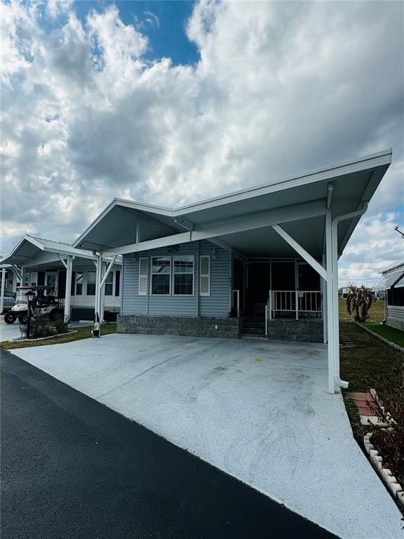 A light blue manufactured home features a large attached carport and a concrete driveway — 603 ARNOLD PALMER DRIVE, DAVENPORT, FL
