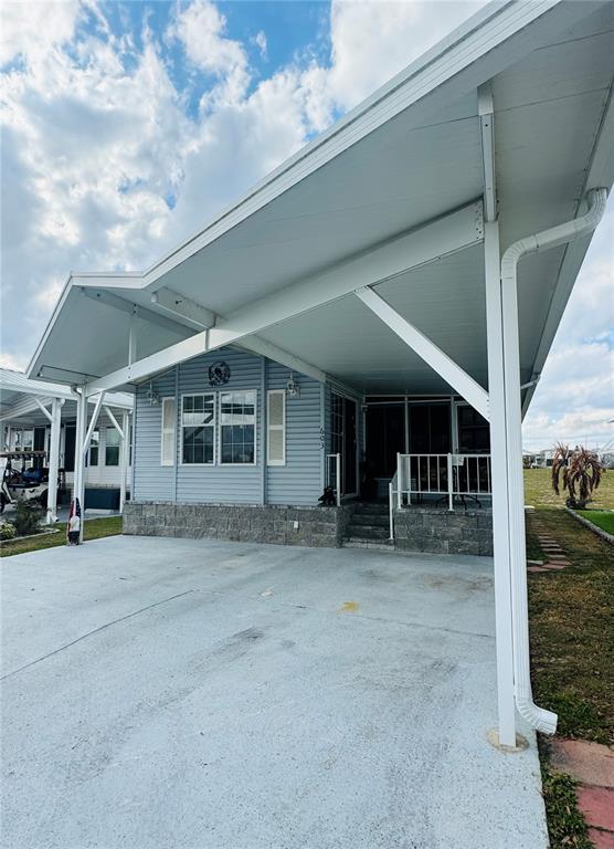 A light blue manufactured home features a large attached carport and a concrete driveway — 603 ARNOLD PALMER DRIVE, DAVENPORT, FL