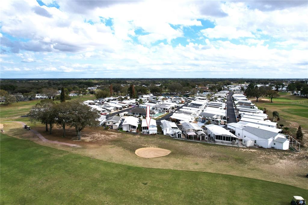 An aerial view shows a manufactured home community bordering a golf course with a sand trap — 603 ARNOLD PALMER DRIVE, DAVENPORT, FL