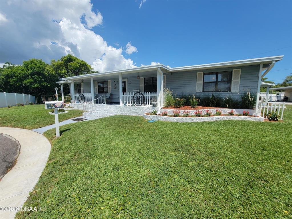 A light blue single-story house features a covered front porch and a landscaped garden bed — 734 SHELDON CIRCLE, PORT ORANGE, FL