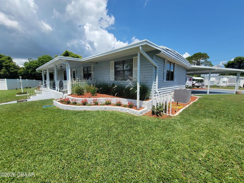 A light blue single-story house features a white porch, landscaping, and a side carport — 734 SHELDON CIRCLE, PORT ORANGE, FL