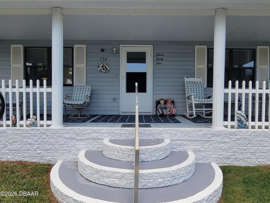 A front porch features curved concrete steps, a white picket fence, and two rocking chairs — 734 SHELDON CIRCLE, PORT ORANGE, FL
