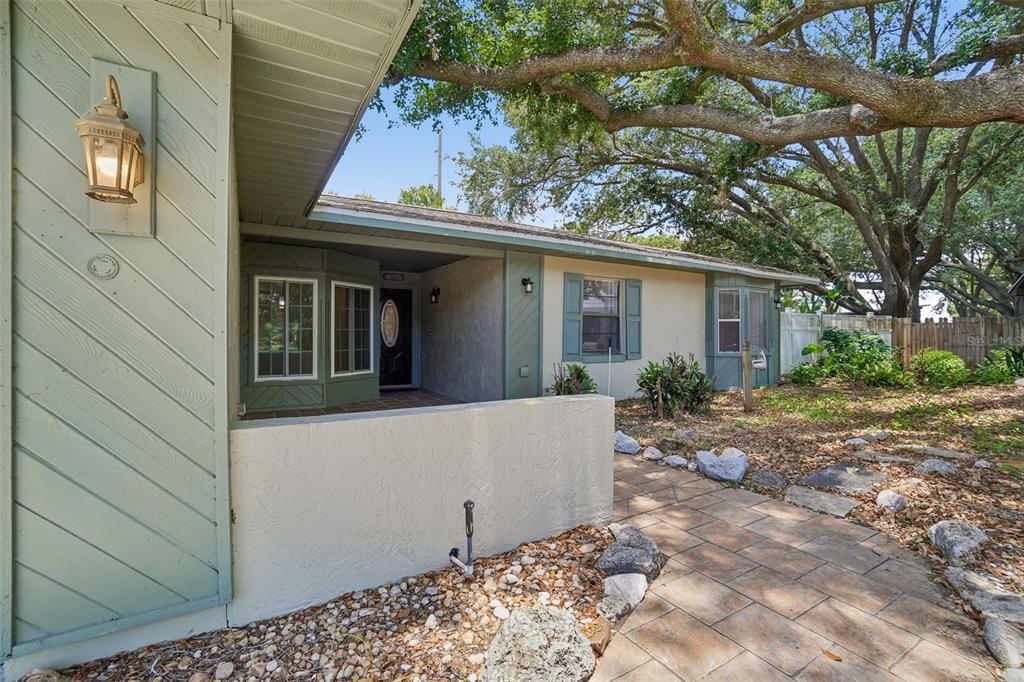 The exterior of a single-story house features a stone walkway, a covered porch, and landscaping — 222 LAKEVIEW DRIVE, AUBURNDALE, FL