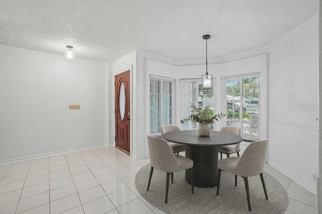A dining area with a round table, four chairs, tile flooring, and a bay window — 222 LAKEVIEW DRIVE, AUBURNDALE, FL