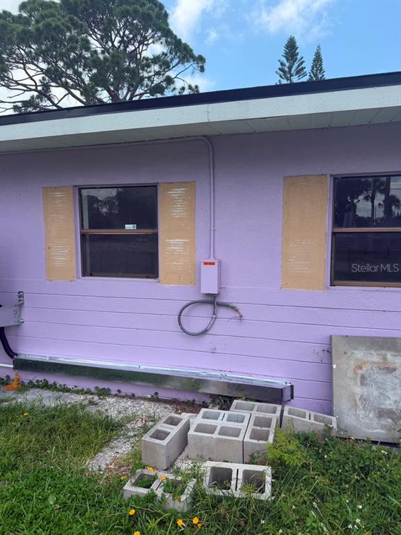 The exterior of a purple house shows two windows with wooden shutters and electrical equipment — 7235 ROYAL PALM DRIVE, NEW PORT RICHEY, FL