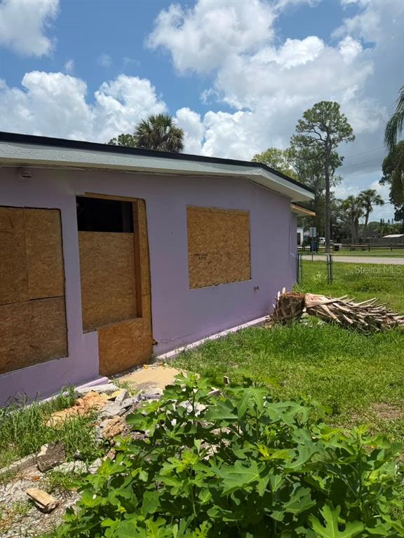 The exterior of a purple house features boarded-up windows and a yard with debris — 7235 ROYAL PALM DRIVE, NEW PORT RICHEY, FL